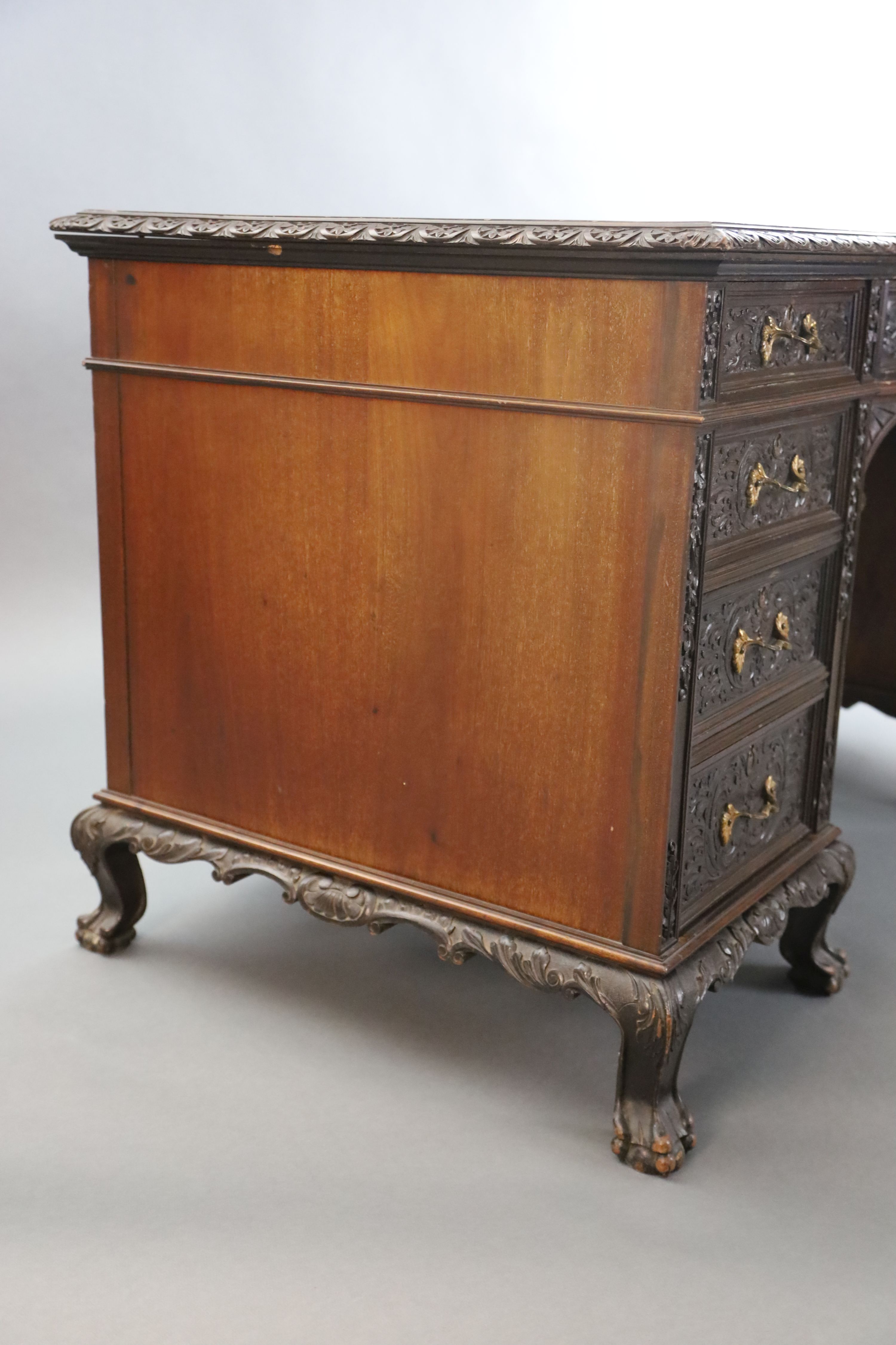 An Edwardian foliate carved mahogany serpentine kneehole desk, W.4ft 6in. D.2ft 5in. H.2ft 6in.